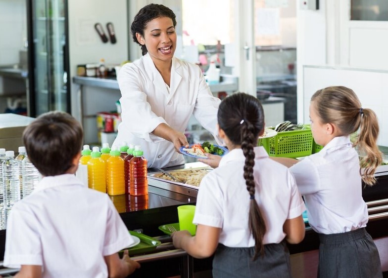 Catering staff serving food to pupils